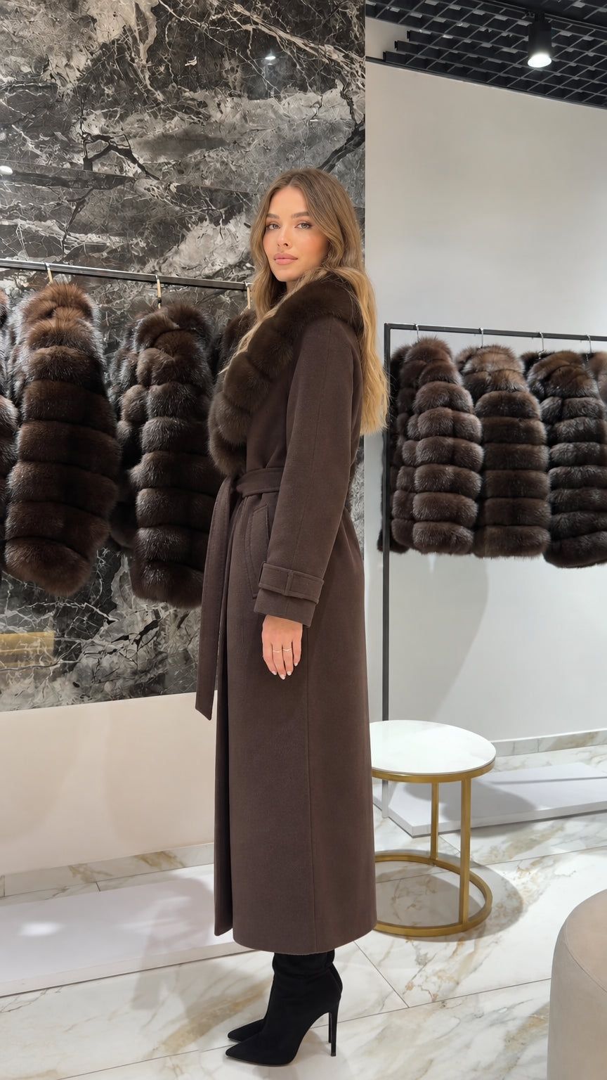 Side profile of woman wearing a long brown coat with waist tie and fur trim