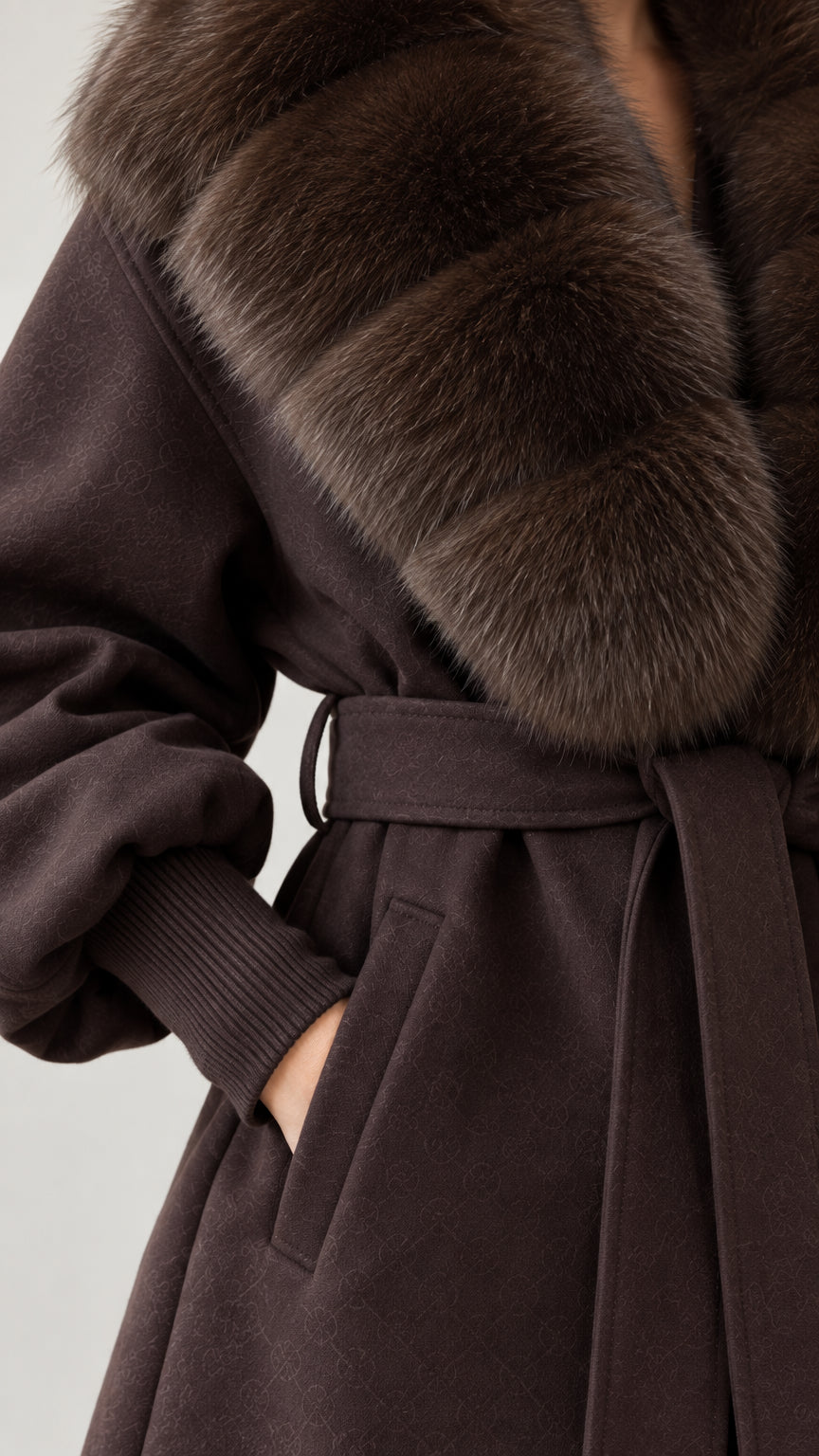 Close-up detail of plush faux fur collar, belt sash, and ribbed cuff on chocolate brown coat