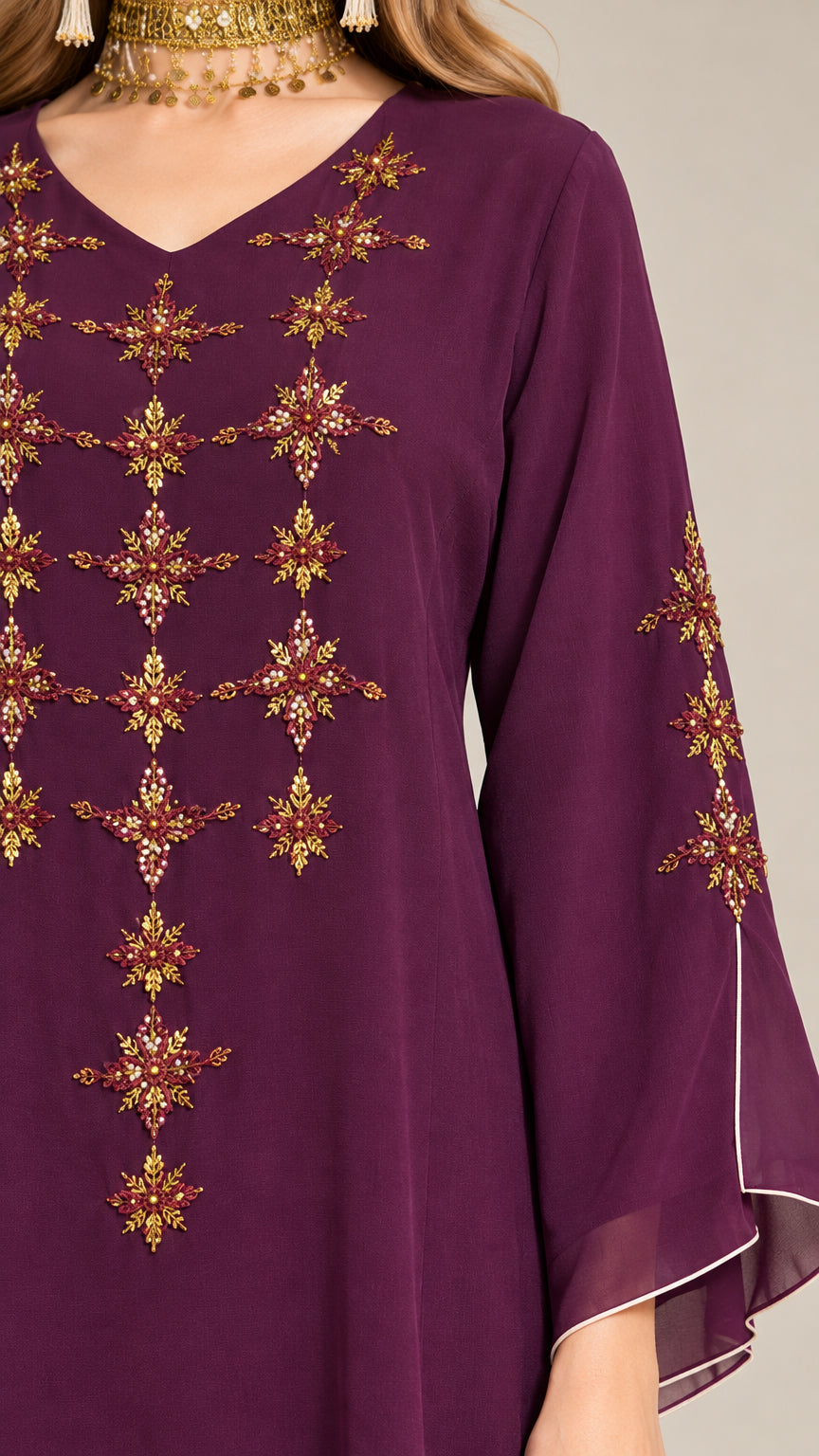 Close-up detail of gold-tone embroidery on bodice and flared sleeve of Plum dress