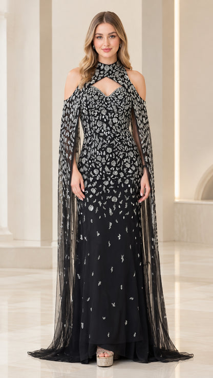 Front view of black beaded halter evening gown with sweeping sheer cape