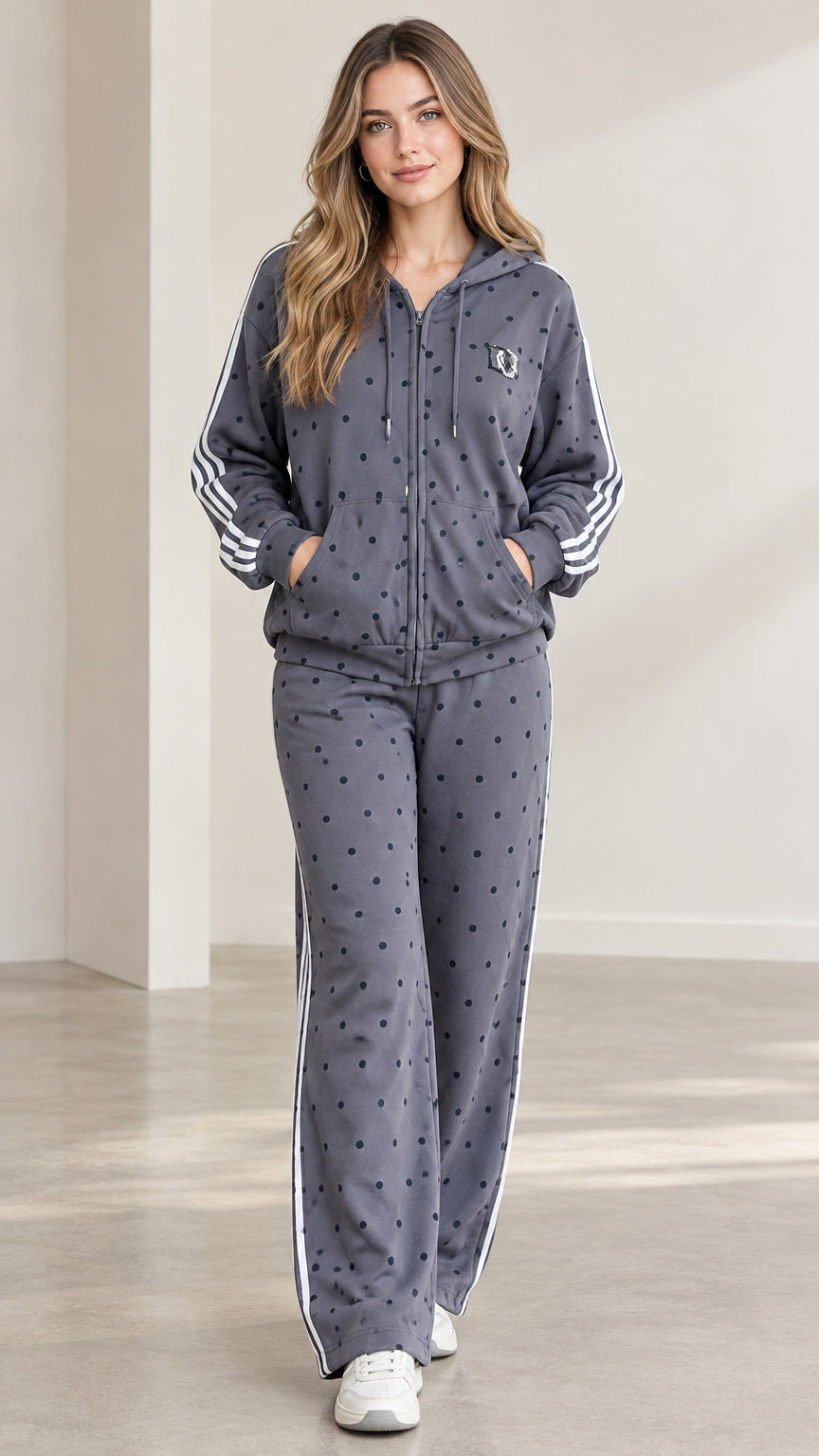 Full front view of model wearing charcoal grey polka dot tracksuit set with white side stripes