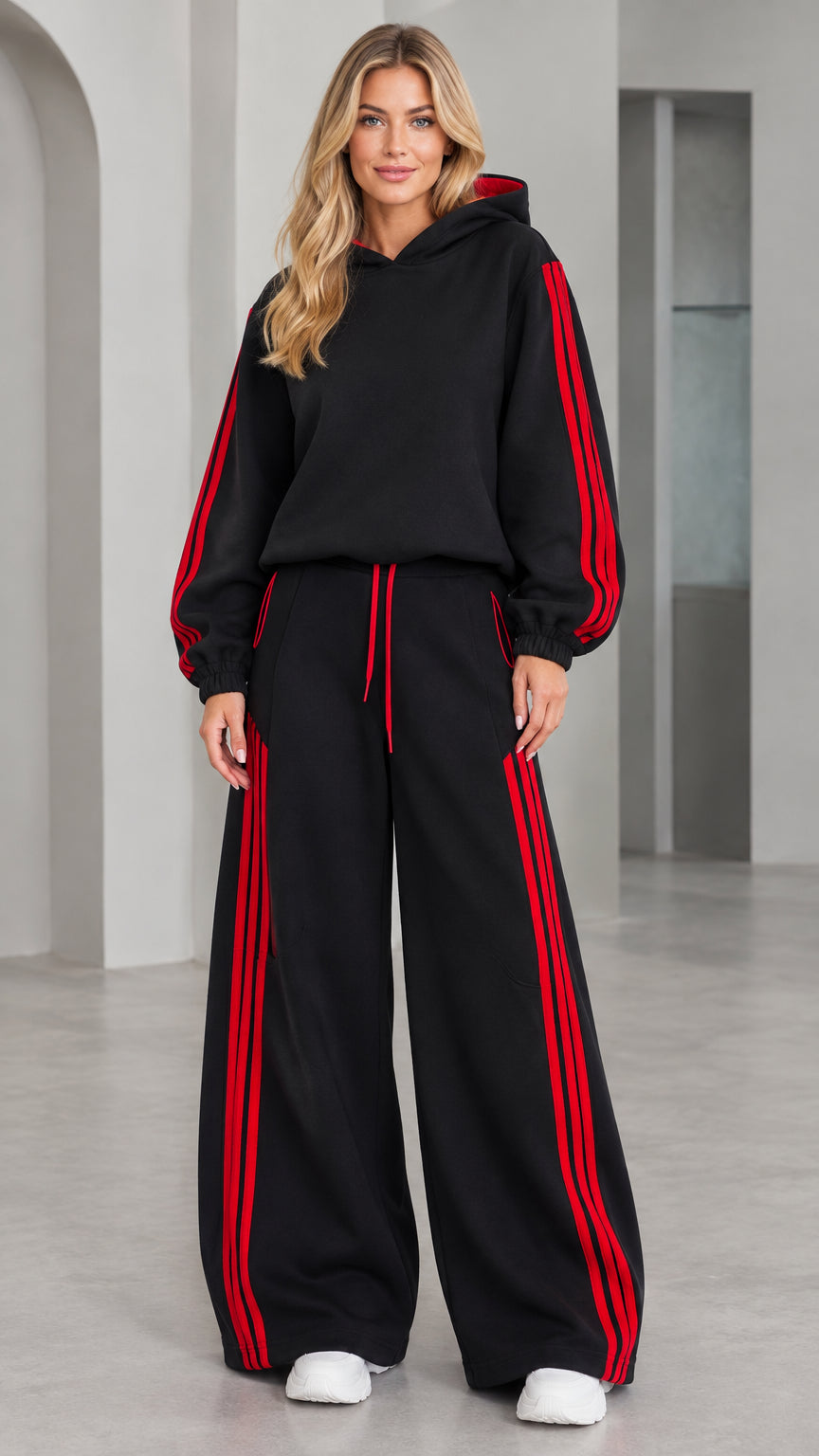 Front view of woman wearing black 2-piece hoodie and wide leg tracksuit set with red stripes