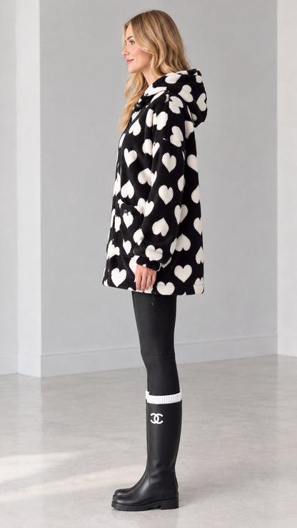 Side view of woman wearing black heart pattern zip-up fleece coat