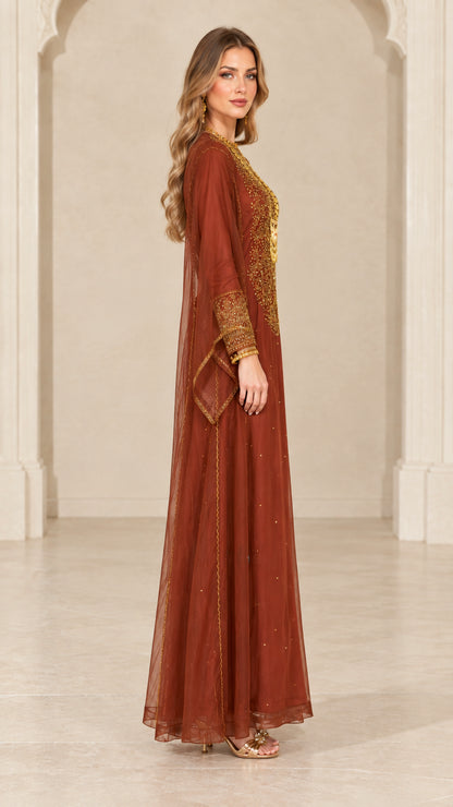 Side profile view of woman modeling rust brown embroidered sheer maxi gown