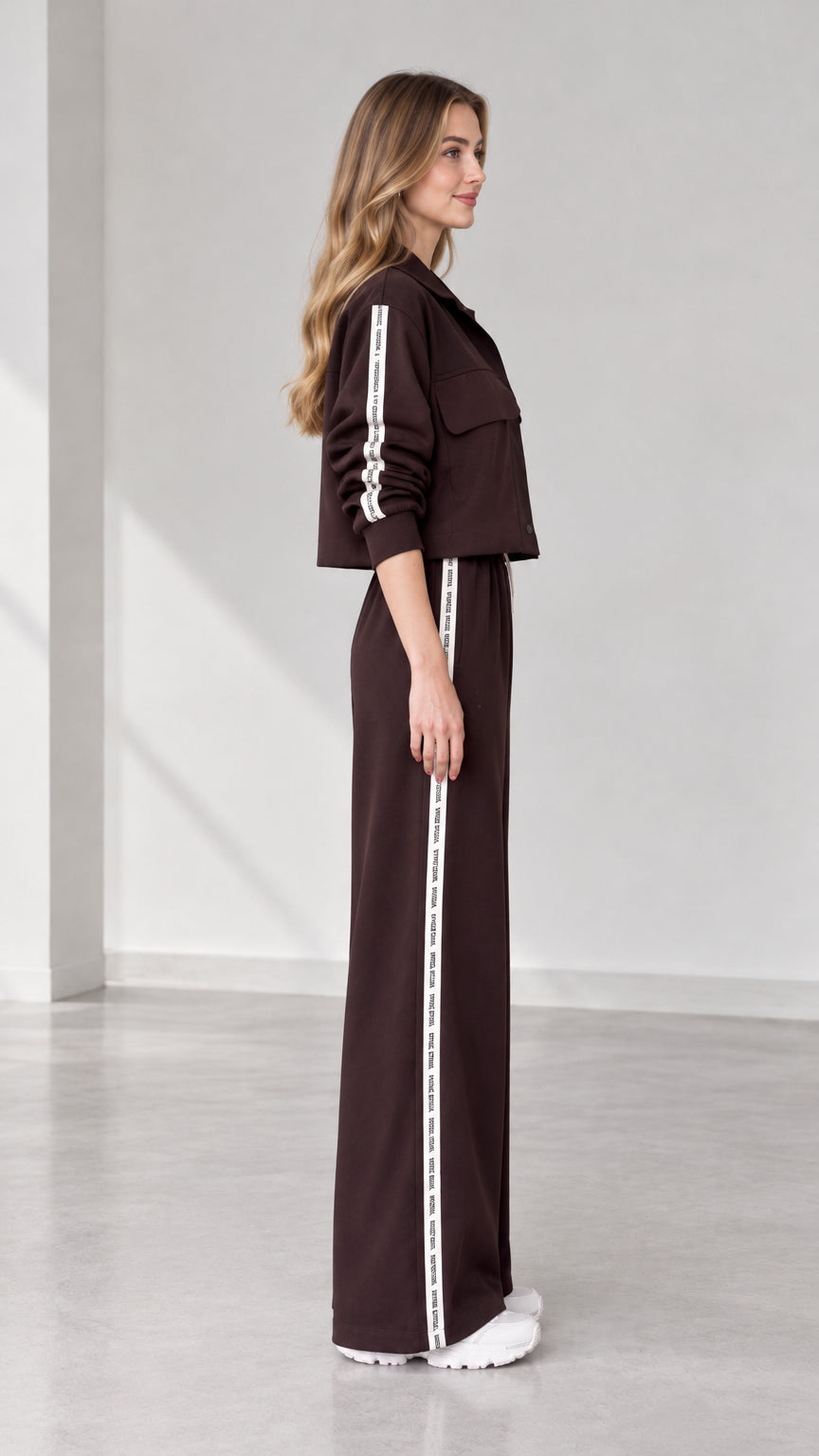 Side profile view of women's dark brown tracksuit set with contrast side stripes