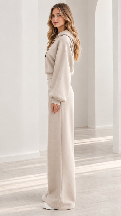 Side profile view of model wearing beige hooded sweatshirt and wide-leg sweatpants