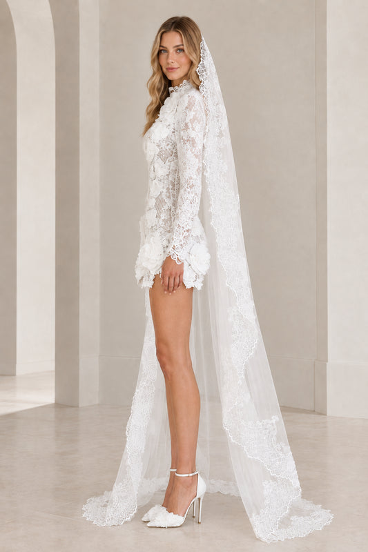 White lace mini dress with 3D floral rosettes and veil cape, side profile view