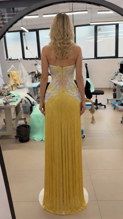 Back view of yellow strapless corset evening dress with long fringe skirt