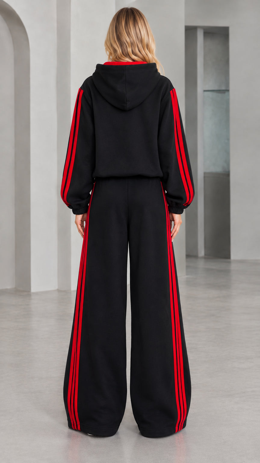 Back view of woman wearing black hooded sweatshirt and wide leg track pants