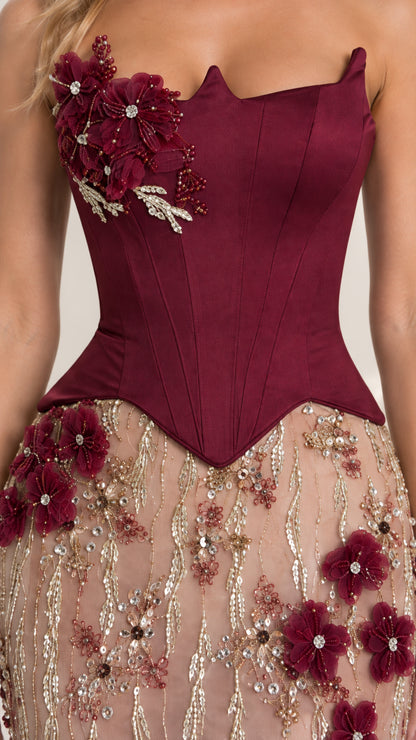 Close-up detail of structured burgundy basque bodice with 3D floral appliqué and beadwork