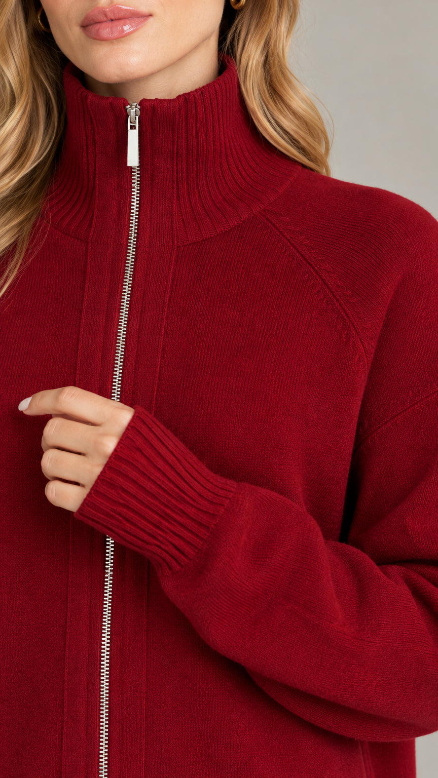 Close-up detail of silver zipper pull, ribbed collar, and knit texture on burgundy cardigan