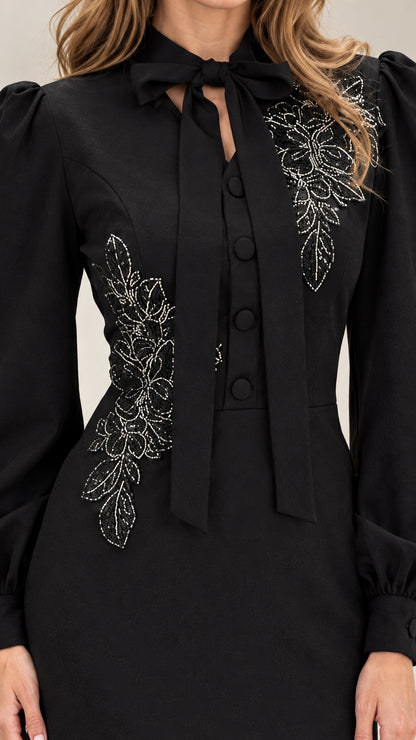 Close-up of bow collar and sparkling floral embroidery on black dress