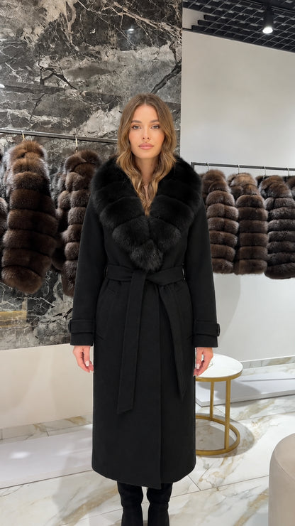Front view of woman wearing a classic black long coat with black faux fur collar