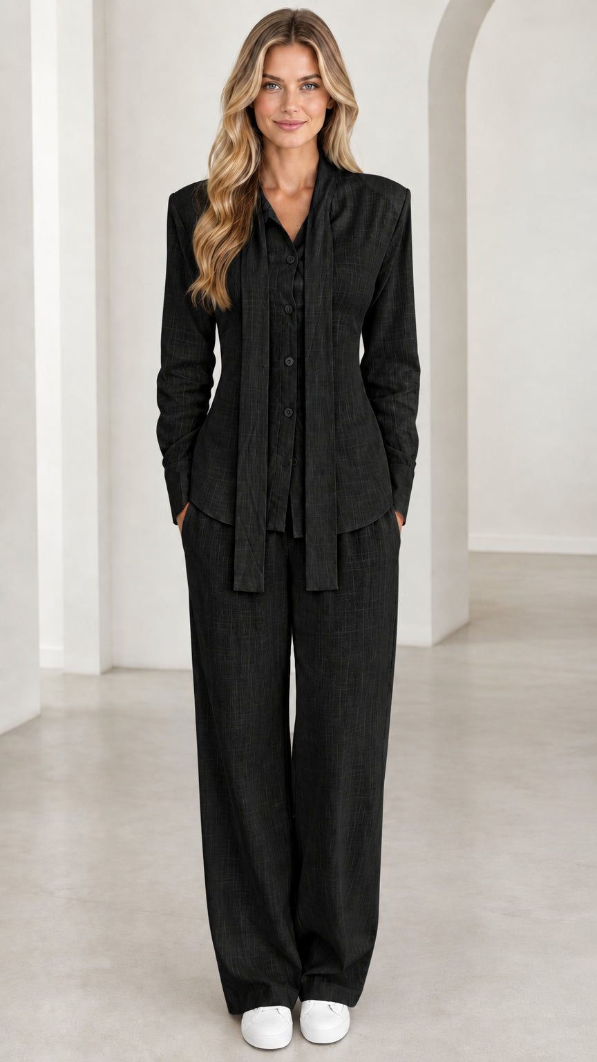 Front view of woman wearing black tie-neck blouse and matching trousers set