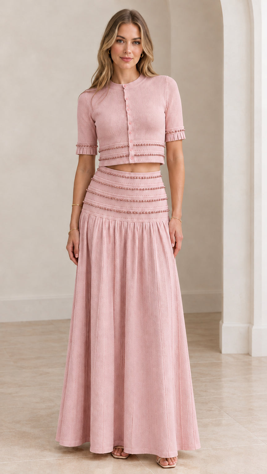 Model wearing blush pink beaded crop top and pleated maxi skirt set