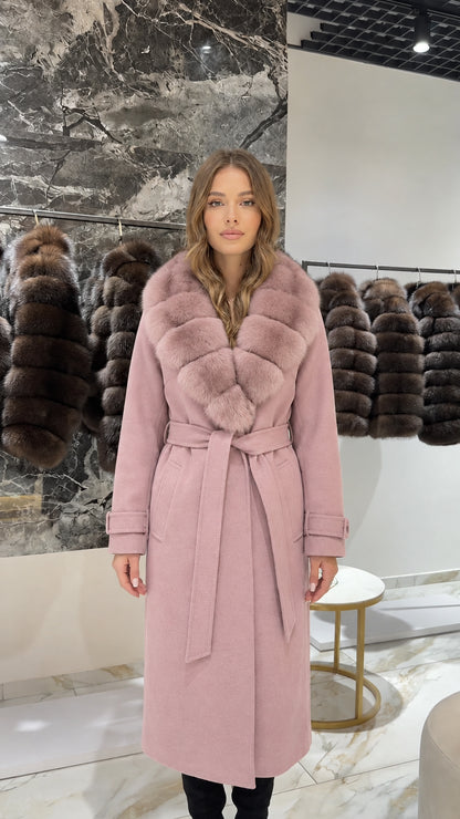 Front view of woman wearing a dusty pink long coat with matching faux fur collar
