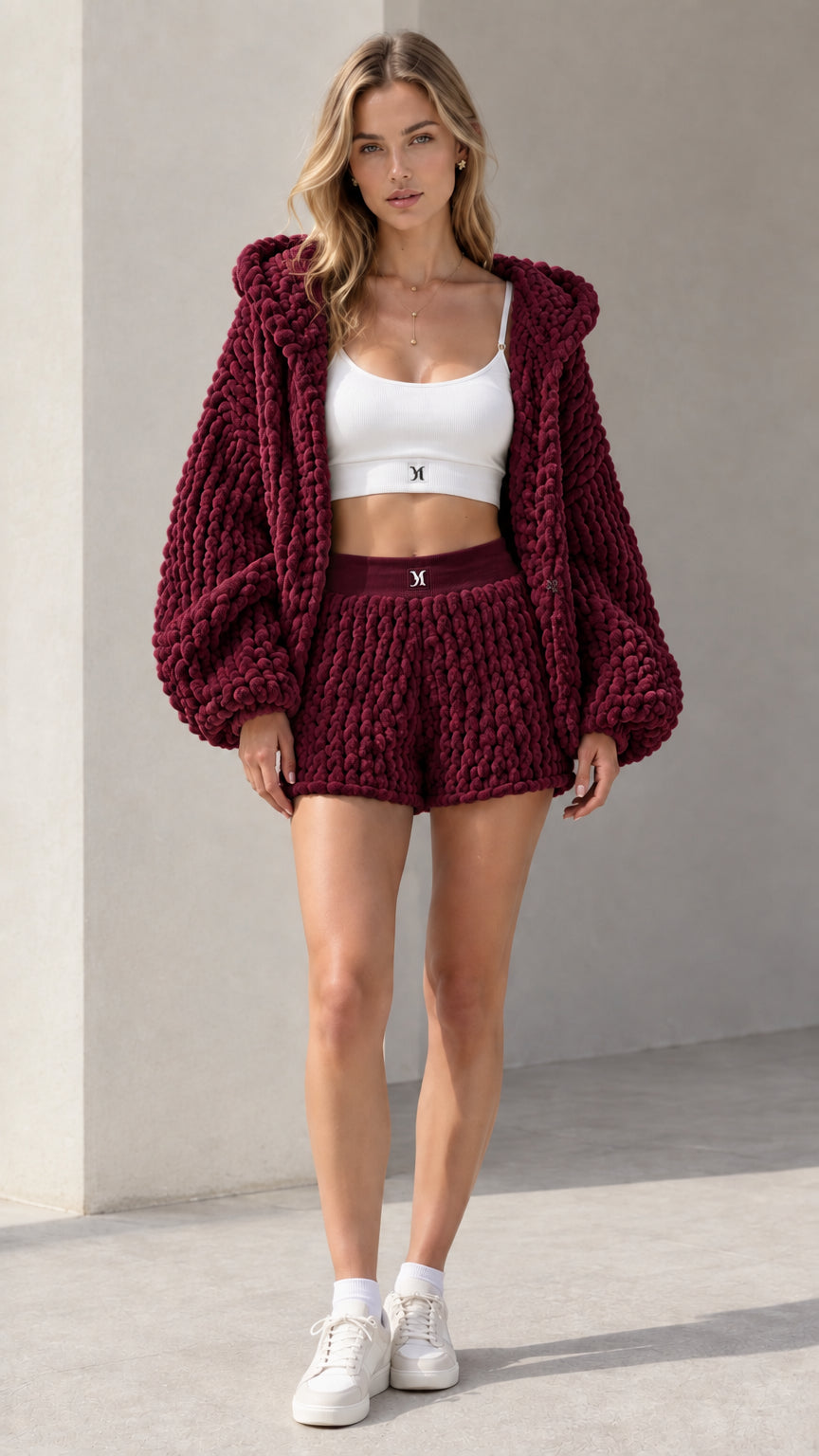 Model wearing rich burgundy chunky knit hooded cardigan and knit shorts set